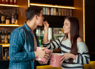 Young couple eating popcorn in cinema cafe