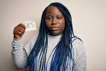 Young african american plus size woman with braids holding reminder paper with yes message with a...