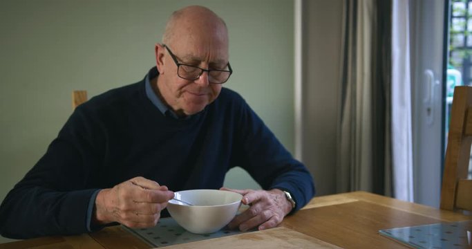 Senior man eating breakfast by the window