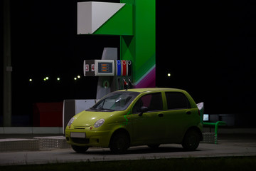 Plakat car at a gas station at night