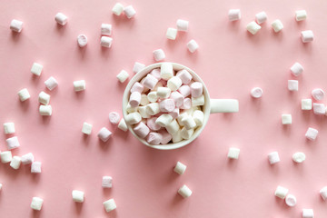 Pink and white mini marshmallows in cup with hot chocolate on pink background