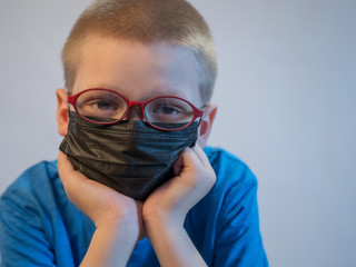 boy in dirty medical masks are quarantined at home. Children cough hard and get dirty with masks quickly. concept of fight against coronavirus epidemic and proper prevention of infections