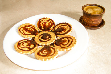 Chocolate decorated cookies laid out on a white plate. A cup of coffee.