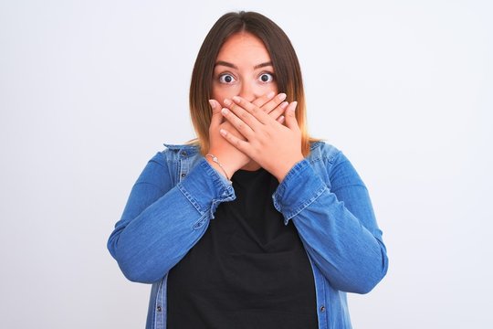 Young beautiful woman wearing denim shirt standing over isolated white background shocked covering mouth with hands for mistake. Secret concept.