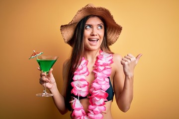 Beautiful woman with blue eyes on vacation wearing bikini and hawaiian lei drinking cocktail...