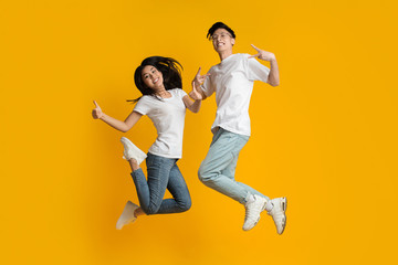 Crazy asian millennial couple jumping in air