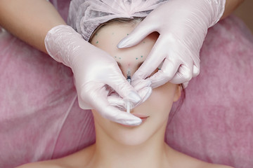 Obraz na płótnie Canvas The doctor cosmetologist makes the Rejuvenating facial injections procedure for tightening and smoothing wrinkles on the face skin of a beautiful, young woman in a beauty salon.Cosmetology skin care