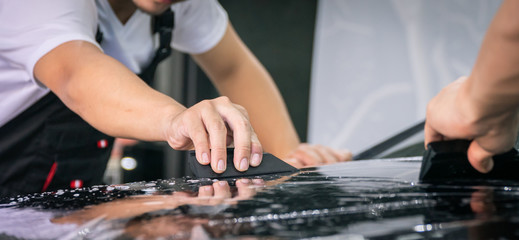 Car wrapping specialist putting vinyl foil or film on car for protection. Selective focused - film effected