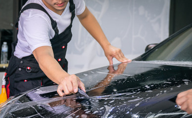 Car wrapping specialist putting vinyl foil or film on car for protection. Selective focused - film...