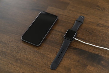 Close-up of smartphone and smartwatch on the wood table.