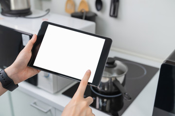 Close-up of hand holding digital tablet at home in kitchen.