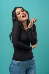 beautiful curvy asian woman with black top and blue jeans on turquoise background happy faces