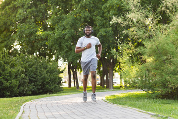 Fototapeta premium Sporty african guy is jogging in the park