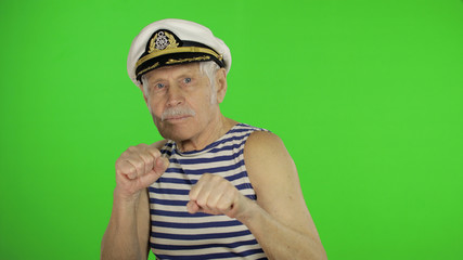 Fototapeta premium Elderly sailor man is angry and shows fists. Sailorman on chroma key background