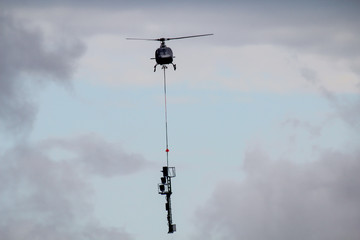 Ein Frachthubschrauber im Zug auf der Bausteller Baustelle, der Masten transportiert