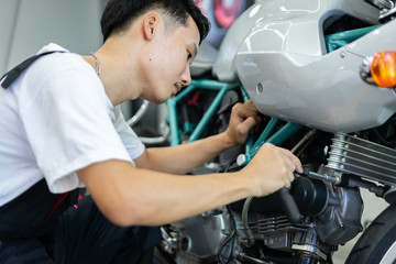 Asian mechanic man fixing the retro motorcycle in the garage