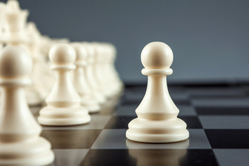 Close-up white pawn on a chessboard, chess, game. The concept of confrontation, career, promotion,...