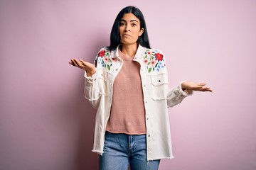 Young beautiful hispanic fashion woman wearing casual sweater over pink background clueless and...