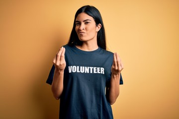 Young beautiful hispanic woman wearing volunteer t-shirt as social charity moral doing money...