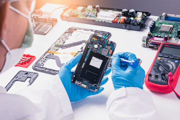 The abstract image of the technician assembling inside of smartphone by screwdriver in the lab. the...