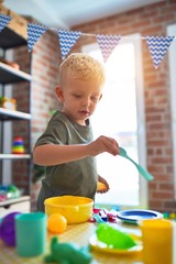 Young caucasian kid playing at kindergarten with toys. Preschooler boy happy at playroom.