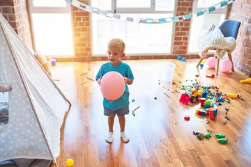 Young caucasian kid playing at kindergarten with toys. Preschooler boy happy at playroom.