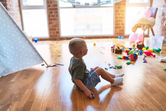 Young caucasian kid playing at kindergarten with toys. Preschooler boy happy at playroom.