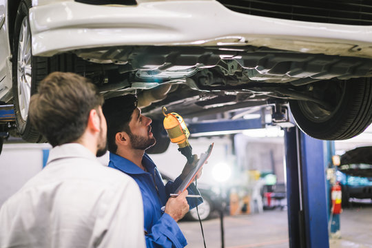 Mechanic holding clipboard with car owner in the workshop garage. Car auto services concepts