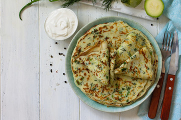 Snack or summer lunch. Zucchini pancakes with greens served with sour cream on a wooden table. Top view flat lay background. Copy space.