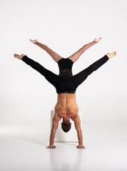 Good shaped man and woman practicing handstand exercise isolated on white background. Strength and...