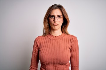 Obraz premium Young beautiful brunette woman wearing casual sweater and glasses over white background depressed and worry for distress, crying angry and afraid. Sad expression.