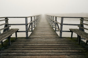 Wooden pier on foggy morning at lake Federsee in Bad Buchau, Germany