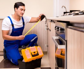 Young repairman working at the kitchen