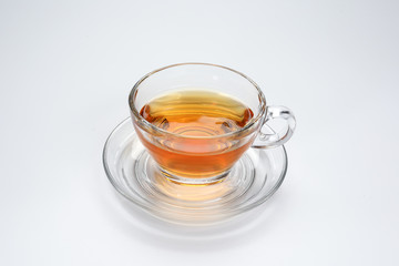 Clear licker tea in a transparent glass cup saucer on white background