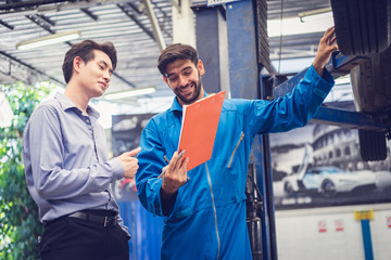 Mechanic holding clipboard with car owner in the workshop garage. Car auto services concepts