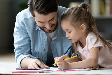 Caring dad drawing in album with little daughter