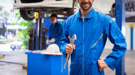 Fototapeta premium Mechanics holding wrench in the workshop garage. Auto car services concepts