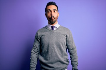 Fototapeta premium Handsome businessman with beard wearing casual tie standing over purple background making fish face with lips, crazy and comical gesture. Funny expression.