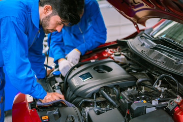 Mechanics checking and repairing the car in a blue suit. Car auto services concepts