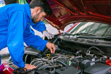 Fototapeta na wymiar Mechanics checking and repairing the car in a blue suit. Car auto services concepts