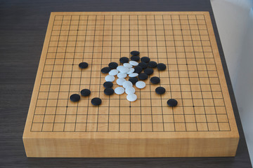 Mix of several black and white go stones on the go board from frontal perspective