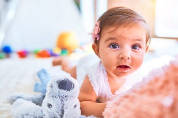 Fototapeta premium Beautiful infant happy at kindergarten around colorful toys lying on blacket