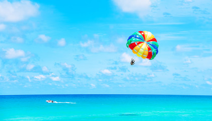 Parasailing above the ocean at tropical islands. Copy space, holiday fun activities.