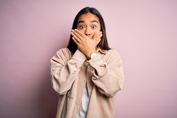 Young beautiful asian woman wearing casual shirt standing over pink background shocked covering mouth with hands for mistake. Secret concept.