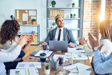 Group of business workers smiling happy and confident. Working together with smile on face applauding one of them wearing king crown at the office