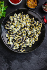 pasta farfalle cuttlefish ink (healthy eating, black multi-colored) menu concept. food background. top view. copy space