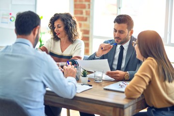 Group of business workers working together. Sitting on desk reading documents at the office