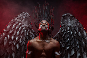 portrait of reckless dark angel with strong muscles, having athletic body, african man in the flesh...