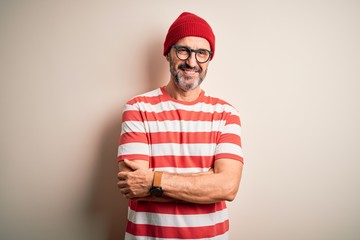 Fototapeta premium Middle age hoary man wearing striped t-shirt glasses and cap over isolated white background happy face smiling with crossed arms looking at the camera. Positive person.