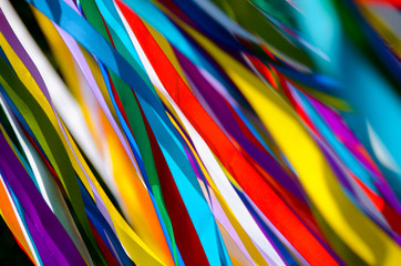 Many multicolored ribbons flutter in the wind in the sun. background